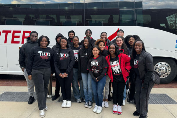 TRIO students pose for a photo in front of a charter bus.